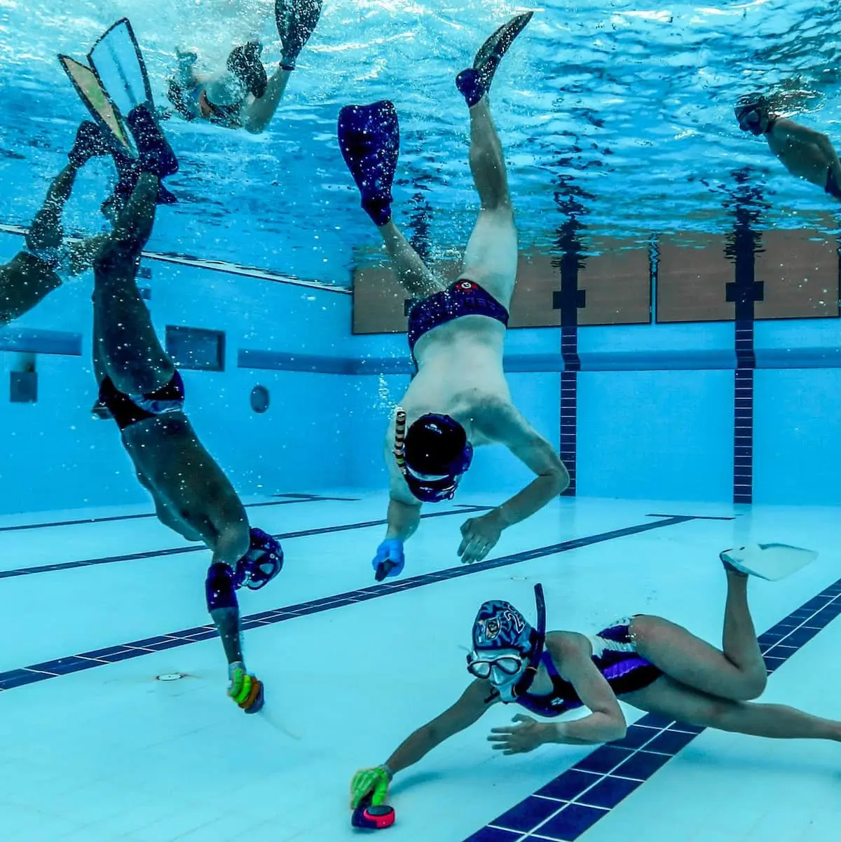 Players competing for the puck on the pool floor during an underwater hockey game